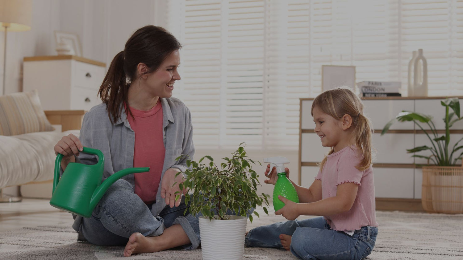 Woman and child playing with green watering cans in a living room.
